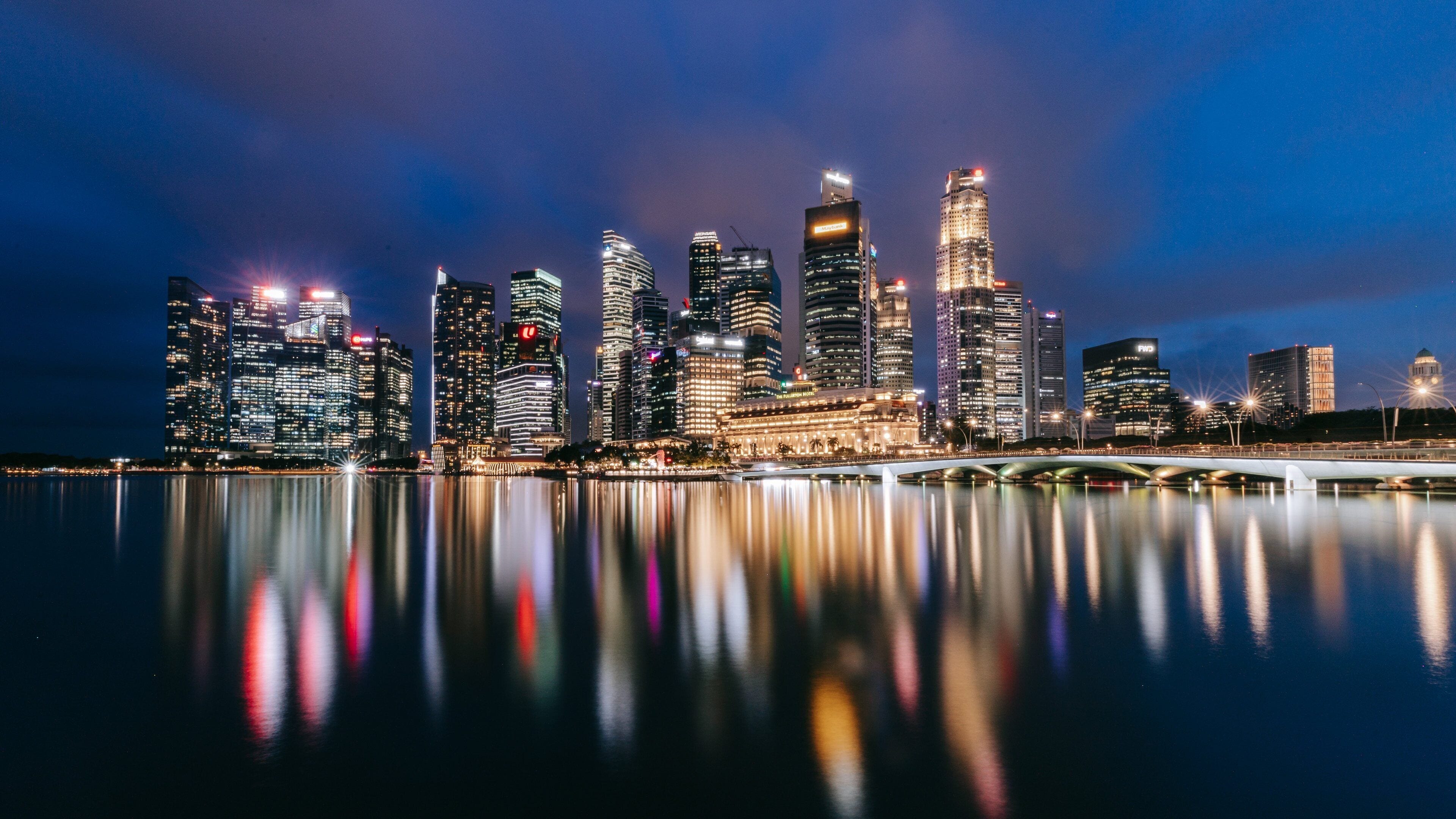 Singapore's Marina Bay business district at dusk, with illuminated office towers reflected in the waterfront